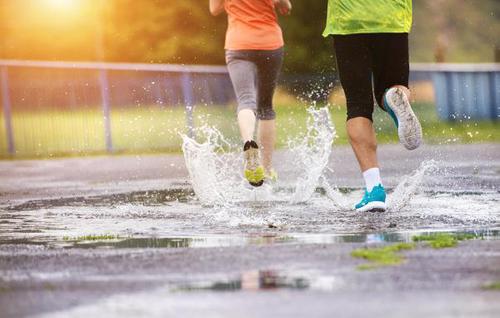 Zwei Jogger laufen durch eine Pfütze